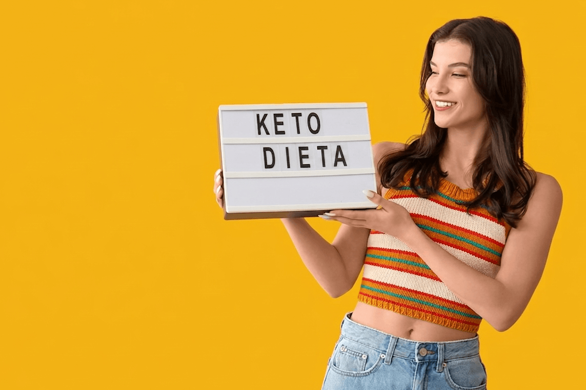 Zadovoljna mlada ženska v rokah drži napis "Keto dieta"