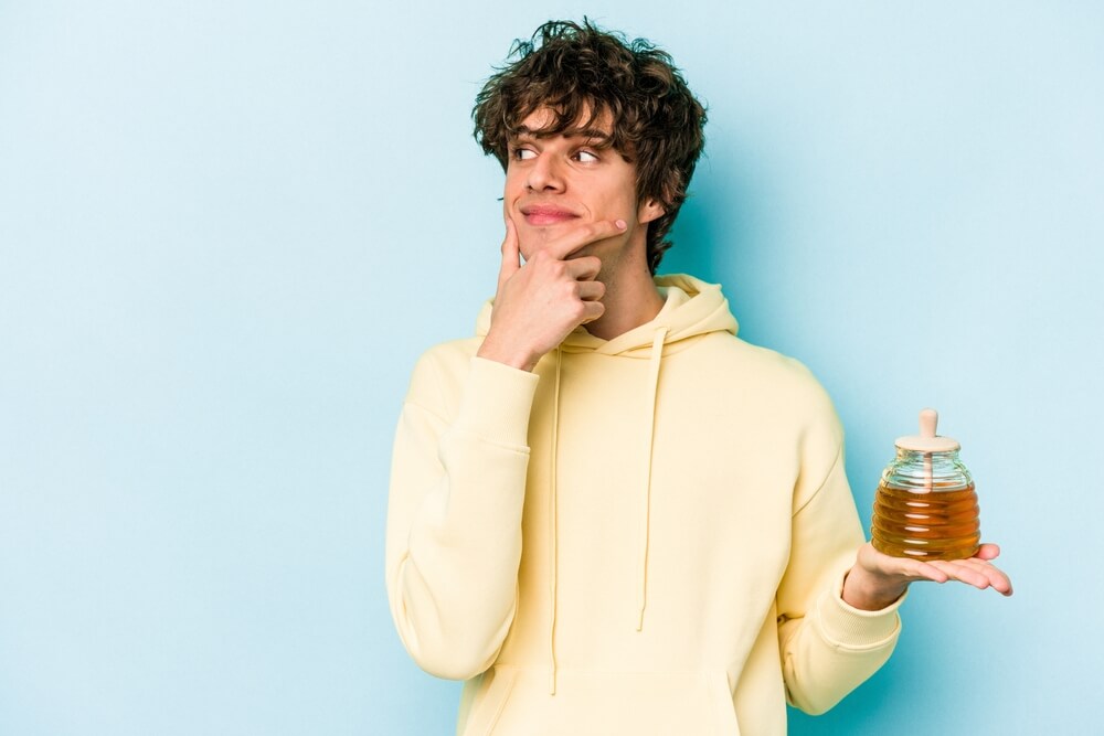 Zamišljen mladenič s stekleničko medu