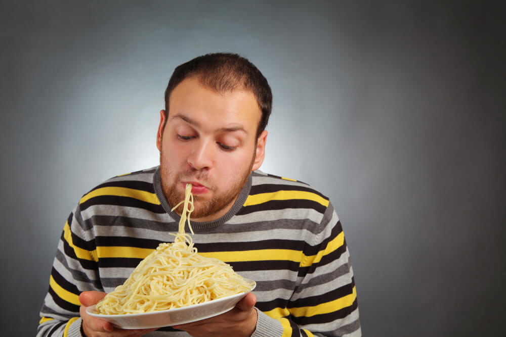 Mladenič sesa špagete z usti s krožnika in uživa v tem