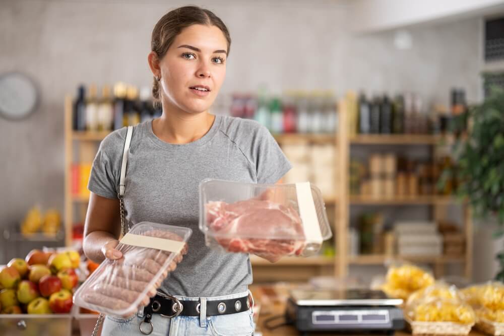 Potrošnica se odloča med nakupom svežega ali predelanega mesa (klobas)